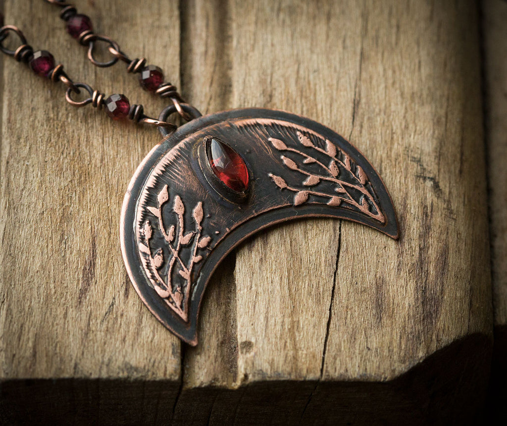 Ciemna lunula z roślinnym rysunkiem i granatami