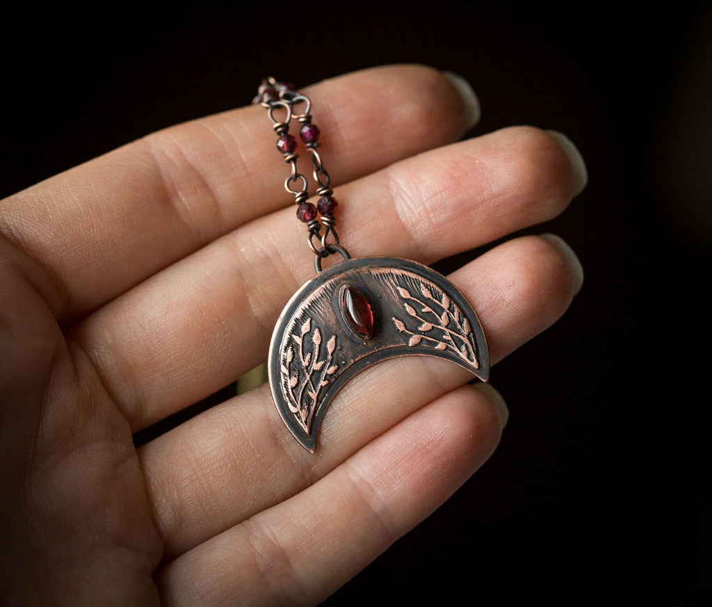 Ciemna lunula z roślinnym rysunkiem i granatami