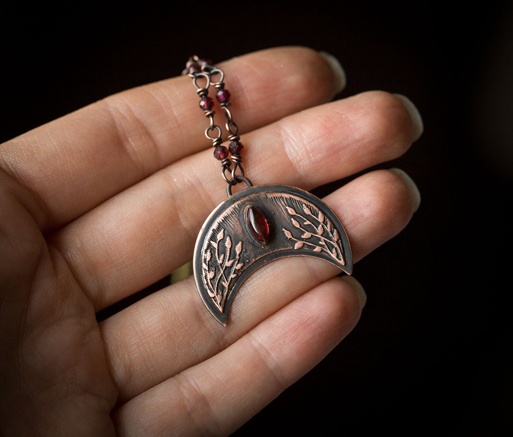 Ciemna lunula z roślinnym rysunkiem i granatami