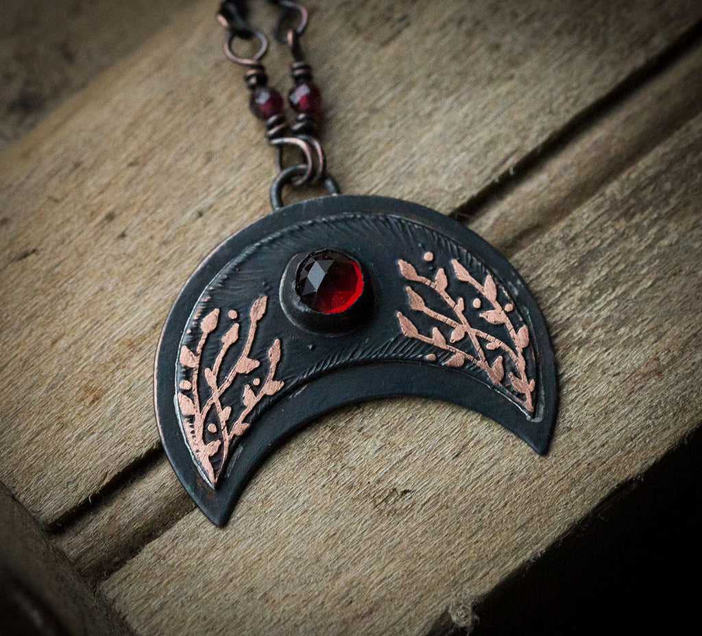 Ciemna lunula z roślinnym rysunkiem i okrągłym granatem