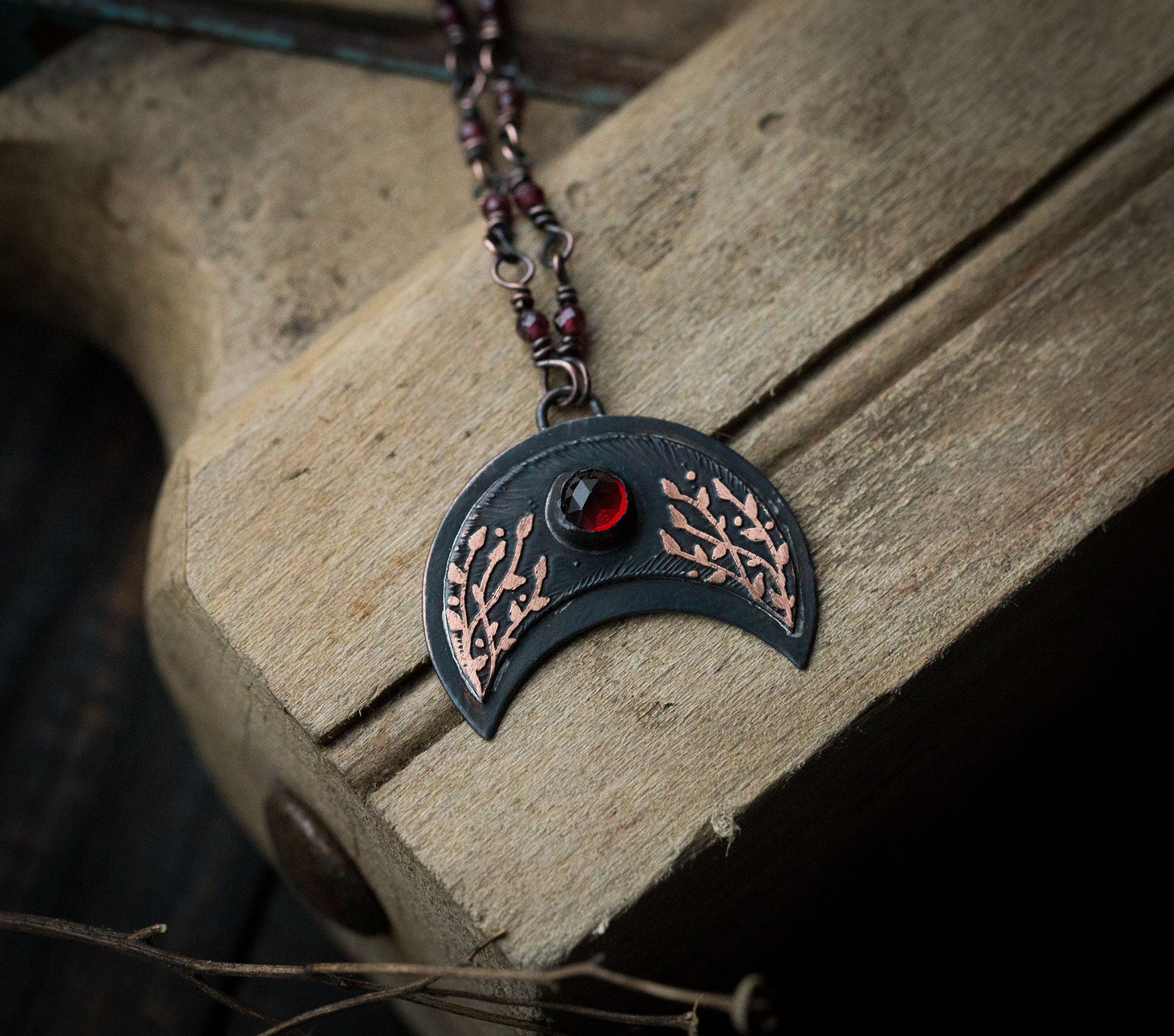 Ciemna lunula z roślinnym rysunkiem i okrągłym granatem