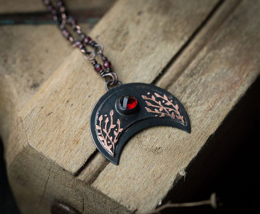 Ciemna lunula z roślinnym rysunkiem i okrągłym granatem