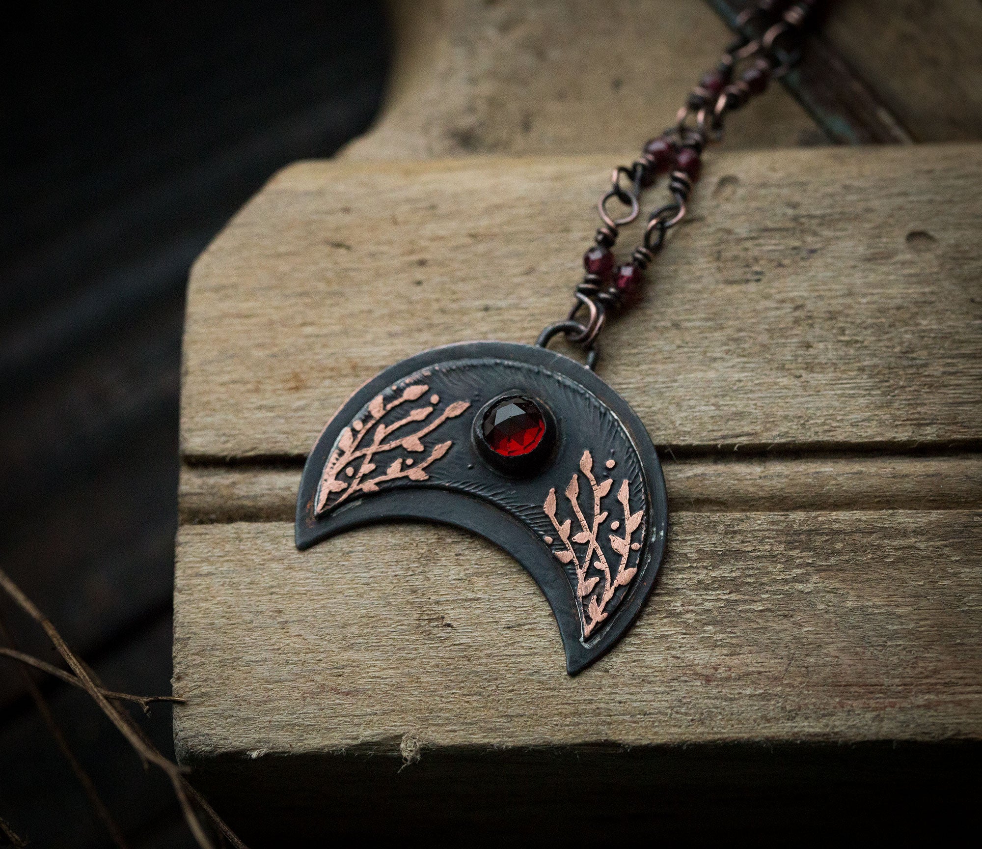 Ciemna lunula z roślinnym rysunkiem i okrągłym granatem