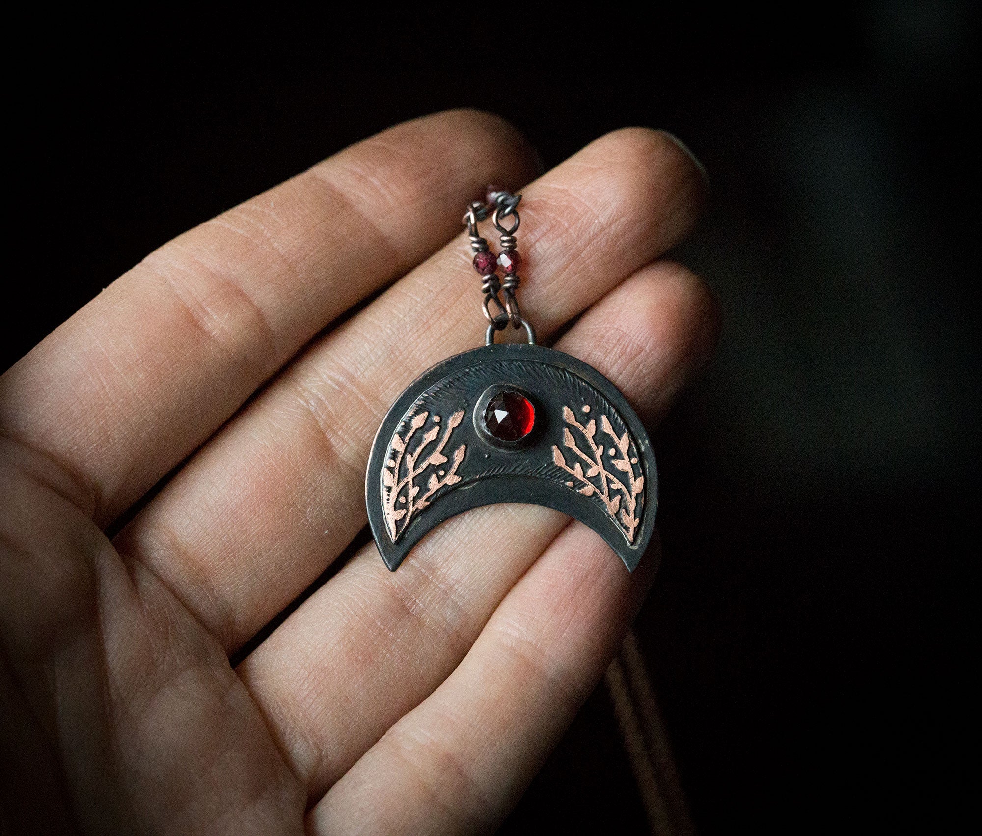 Ciemna lunula z roślinnym rysunkiem i okrągłym granatem