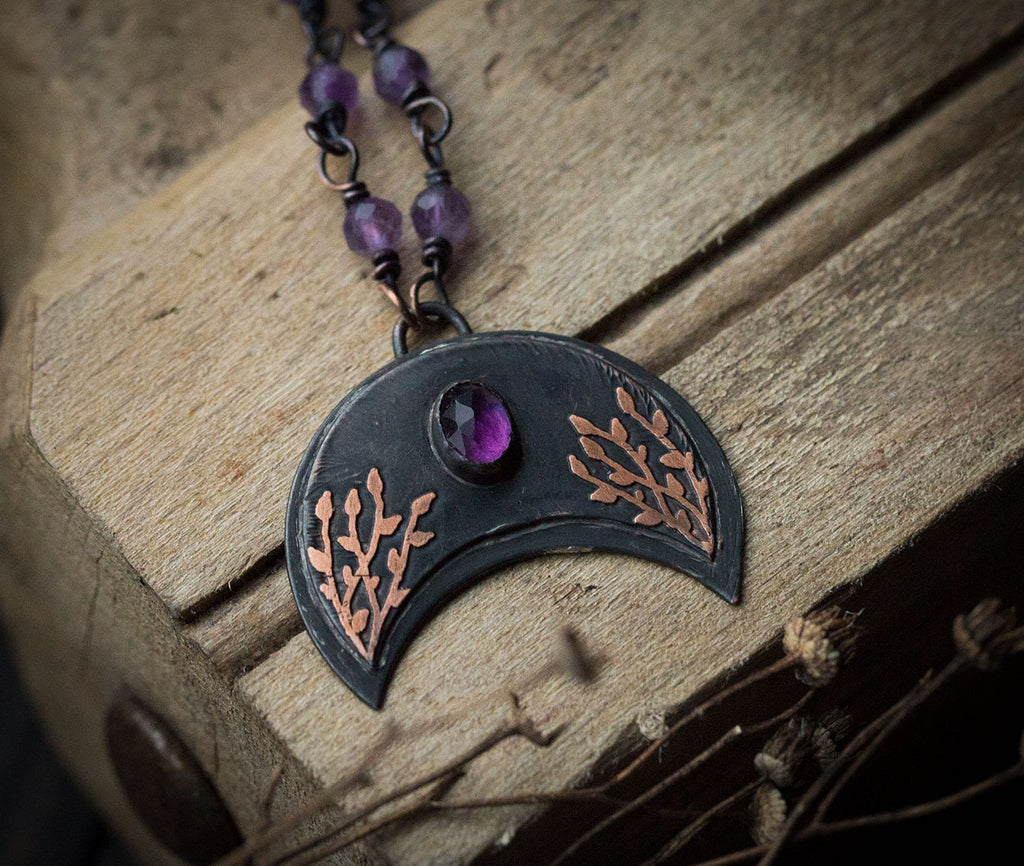 Ciemna lunula z roślinnym rysunkiem i ametystem