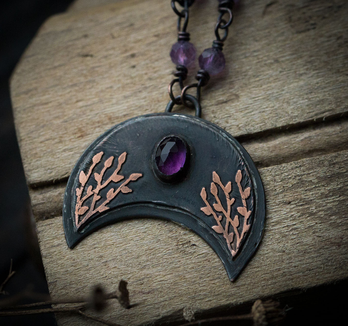 Ciemna lunula z roślinnym rysunkiem i ametystem