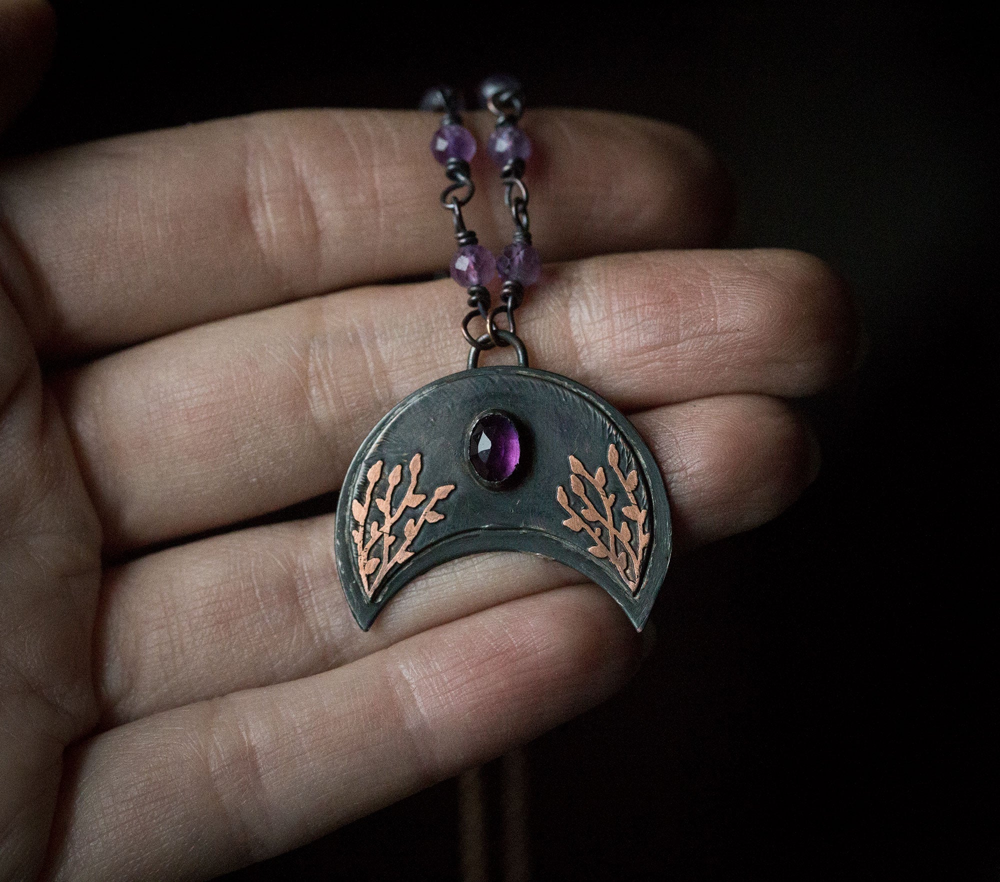 Ciemna lunula z roślinnym rysunkiem i ametystem